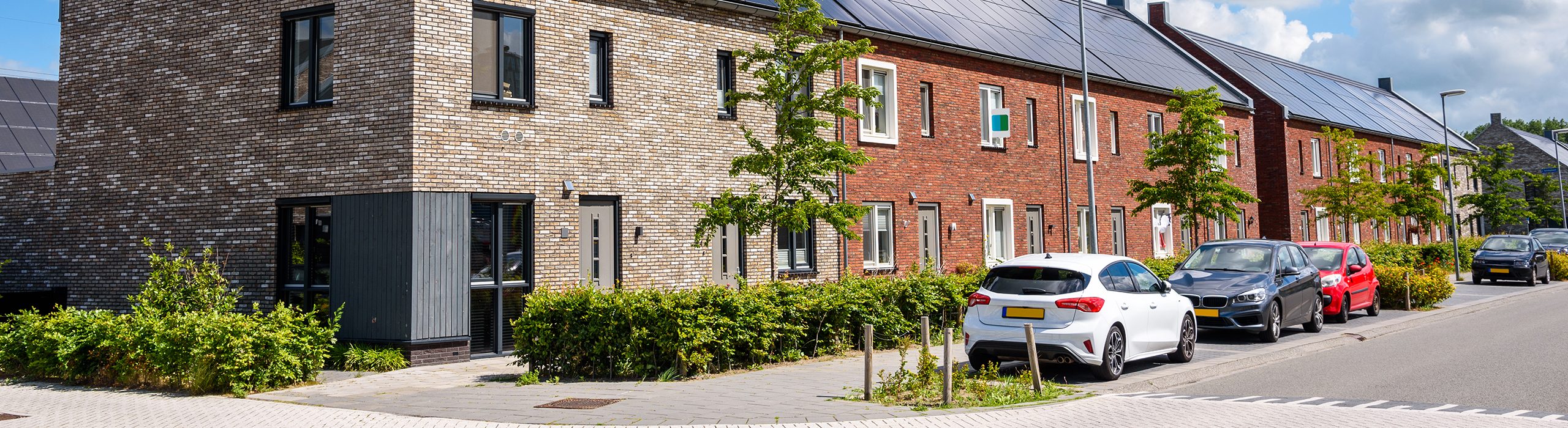 Row of new energy efficient brick terraced houses with the rooftop covered with solar panels on a sunny summer day. Groningen, Netherlands.